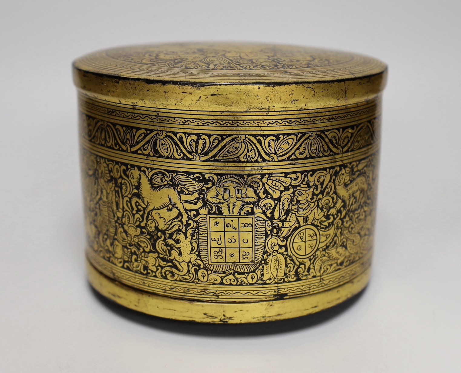 A Burmese gilt decorated papier mache cylindrical box and cover, 14cms high